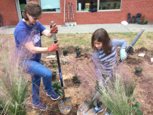 Kingswood parent and student dig holes for native plants in the school's rain garden