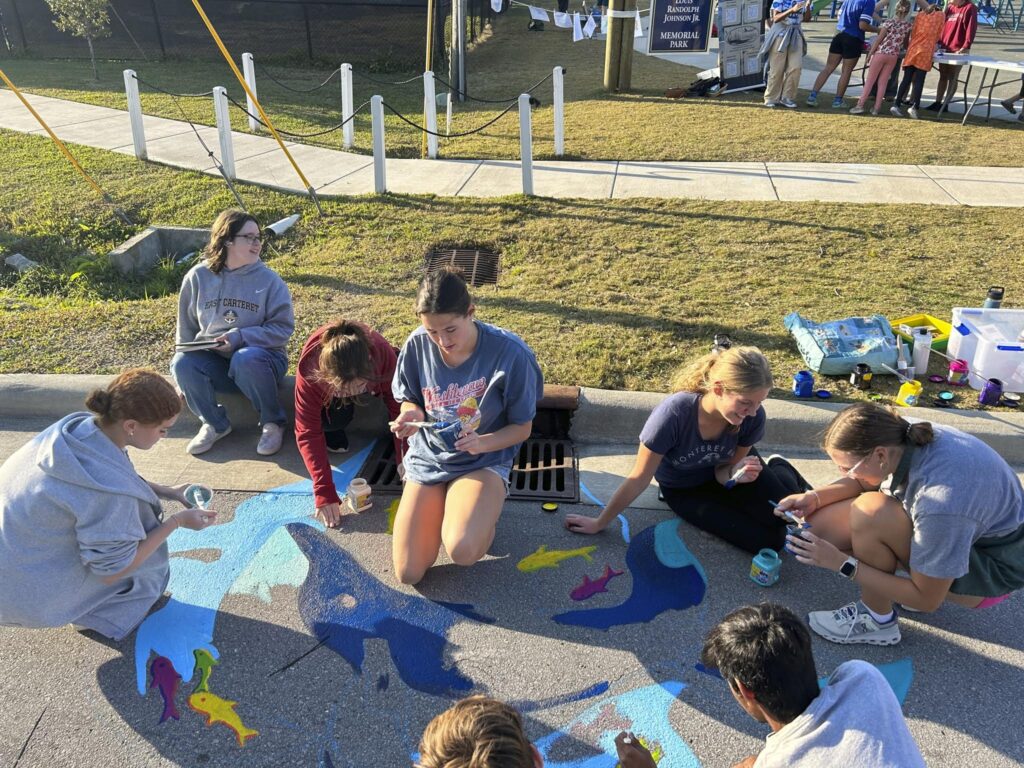 East Carteret High School students decorate a storm drain with a painting of a whale.
