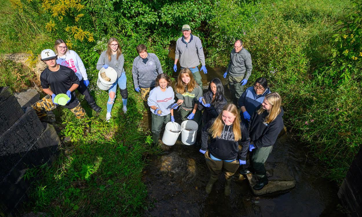 Students help Jerry Miller pick up trash from a creek as part of the CCRG project.
