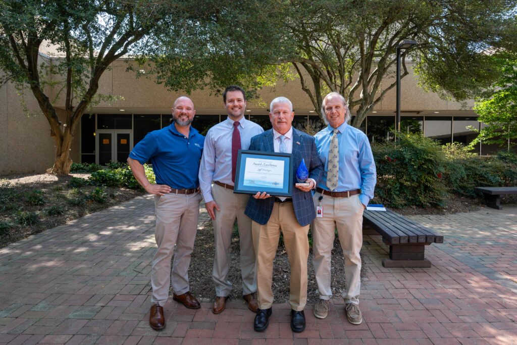 Four men posing with an award